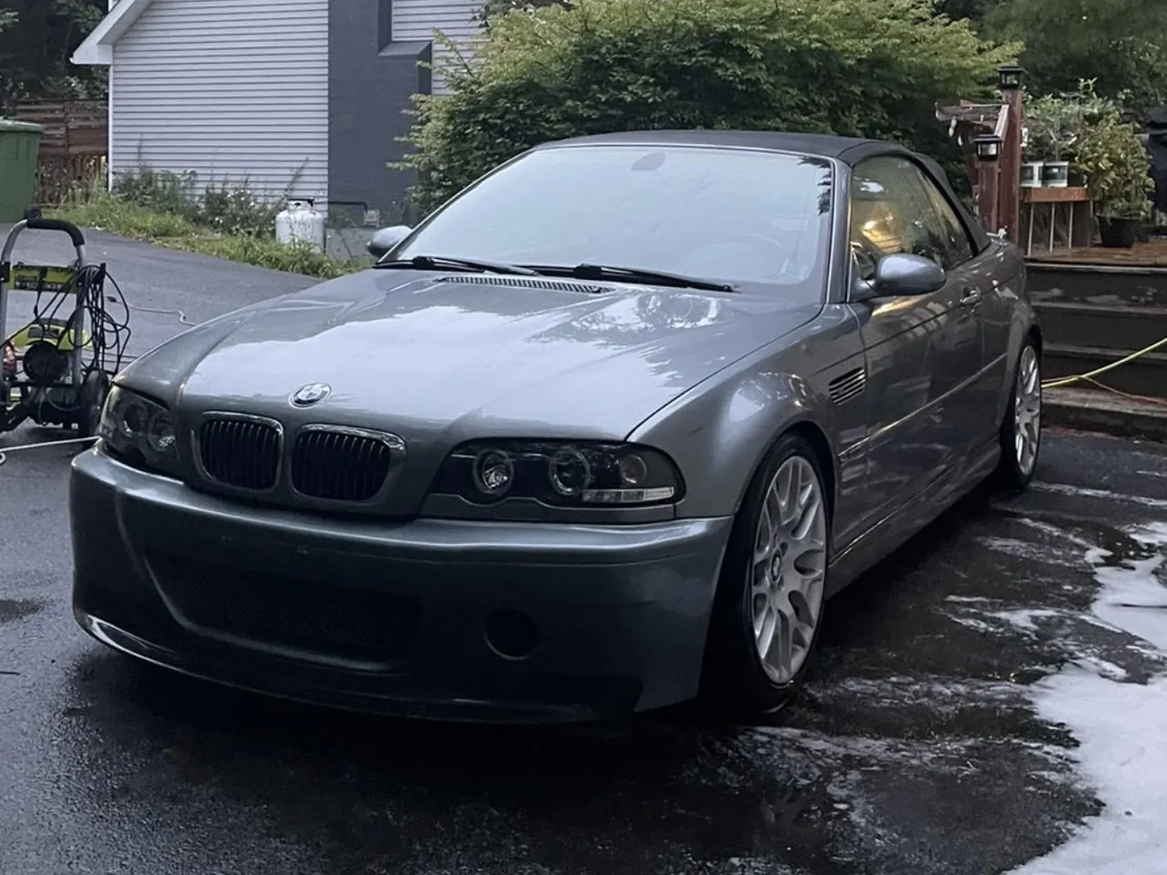 A grey BMW E46 coupe on a wet driveway