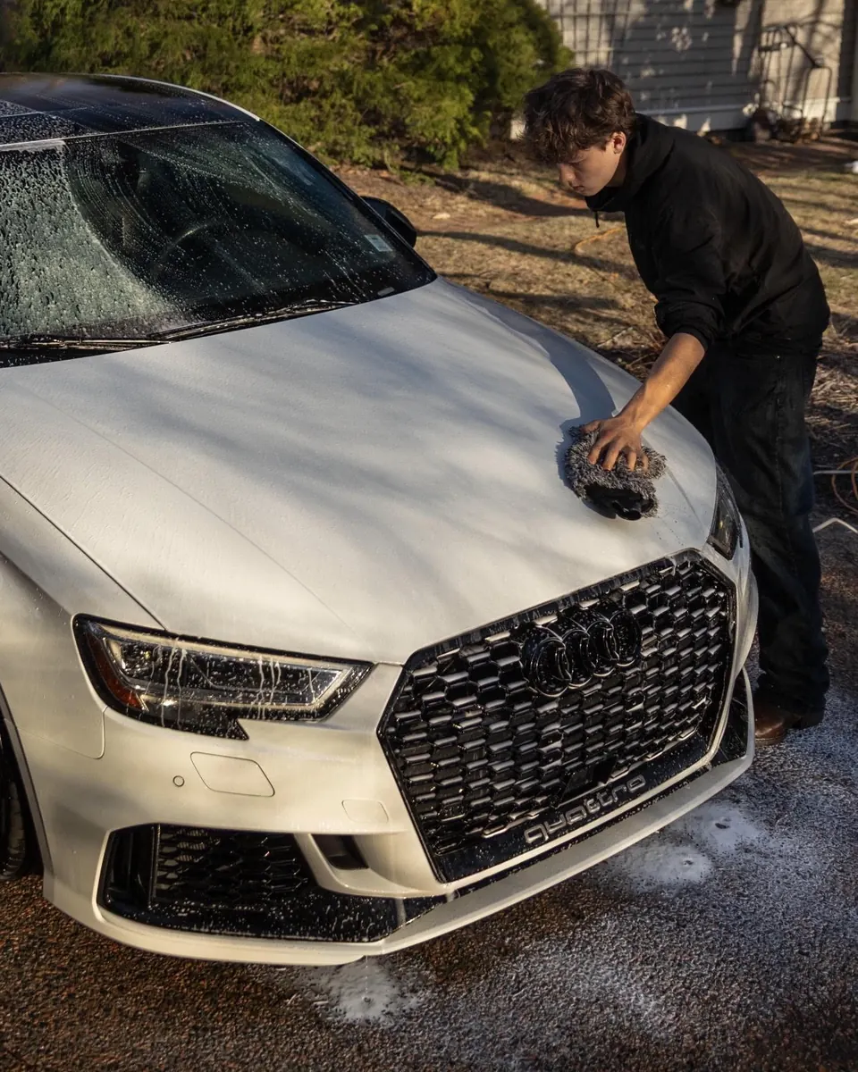 Jake hand washing the hood of a white Audi RS 3 with a wash mitt